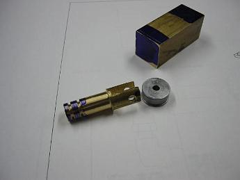  I started working on the water pump assembly.  Shown is the pump ram made from brass, and follower roller in steel.  Waiting with layout blue ends is the pump body.  Based on the drawings, I will scribe lines in the layout blue showing where the cuts and holes need to be.  Oct-2002.